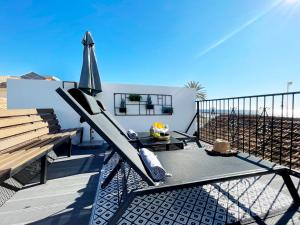 eine Terrasse mit einem Sonnenschirm, einem Tisch und einer Bank in der Unterkunft MalagadeVacaciones - Casa pulpo in Málaga