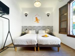 MalagadeVacaciones - Casa pulpo في مالقة: غرفة نوم مع سرير عليه صينية برتقال