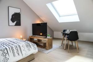 a bedroom with a bed and a table with a tv at L'atticisme : Jacuzzi & Parking in Voiron