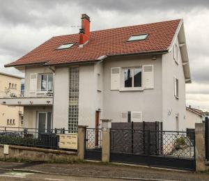 a white house with a red roof and a fence at L'atticisme : Jacuzzi & Parking in Voiron