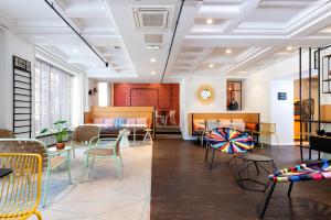 Un vestíbulo con sillas y mesas en una habitación. en ibis Styles Macon Centre, en Mâcon