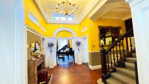 a hallway with yellow walls and a staircase with a grand piano at Kirkhill Estate Rooms in Gorebridge