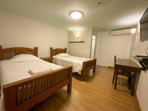 a bedroom with two beds and a table and a desk at Mali's Room in Chiang Mai