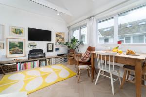 a living room with a dining room table and a yellow rug at 8 Beach Court in St Ives
