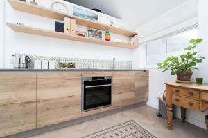 cocina con paredes blancas y armarios de madera en 8 Beach Court en St Ives