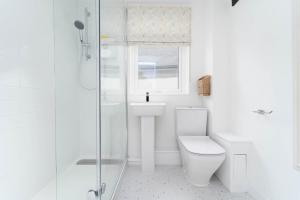 uma casa de banho branca com um WC e um chuveiro em 8 Beach Court em St. Ives