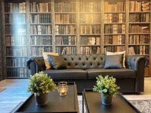 a living room with a couch in front of a wall of books at NEW - Bat'Appart - DIJON - Insolite in Longvic