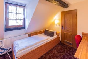 a small bedroom with a bed and a window at Hotel Goldener Hirsch in Suhl