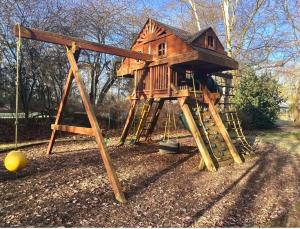 a tree house with a slide and a playground at Deluxe 4 5 Bed Hot Tub Cinema Room 15 in Saffron Walden