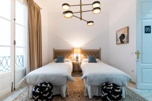 Habitación con 2 camas, paredes blancas y lámpara de araña. en Hostal Roomsole, en Sevilla