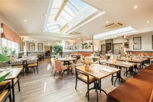 a restaurant with wooden tables and chairs and a skylight at The Fox at Willian in Letchworth