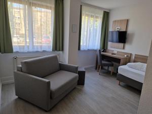 una camera d'albergo con divano, letto e scrivania di Hotel Ladage a Francoforte sul Meno