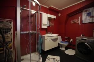 La salle de bains rouge est pourvue d'une douche et de toilettes. dans l'établissement Small apartment Havøysund, à Havøysund