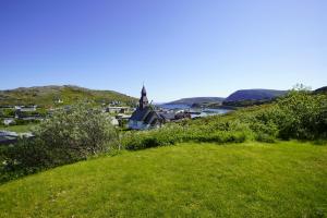 a green hill with a small town and a church at Small apartment Havøysund in Havøysund