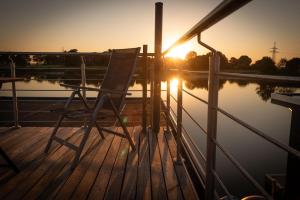 einen Stuhl auf einem Steg mit Sonnenuntergang in der Unterkunft Hausboot Wangermeer Nordsonne12 mit Sauna in Wangerland