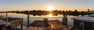 ein Dock mit einem Boot auf dem Wasser bei Sonnenuntergang in der Unterkunft Hausboot Wangermeer Nordsonne12 mit Sauna in Wangerland