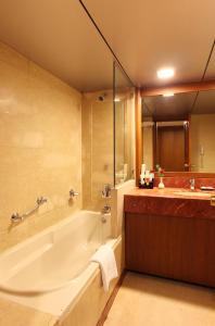 La grande salle de bains est pourvue d'une baignoire et d'un lavabo. dans l'établissement Hotel Aurora Towers, à Pune