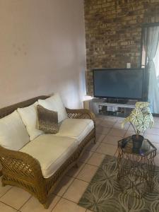 sala de estar con sofá y TV de pantalla plana en A Pousada Guesthouse en Nelspruit