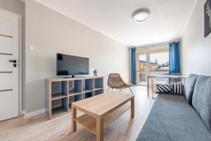 a living room with a couch and a tv and a table at Kopernika, Sun & Snow in Ustka