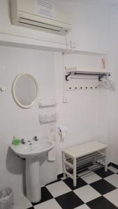 a white bathroom with a sink and a mirror at Pensión San Benito Abad in Seville +37 photos
