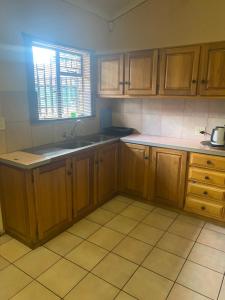 una cocina con armarios de madera y fregadero en A Pousada Guesthouse, en Nelspruit