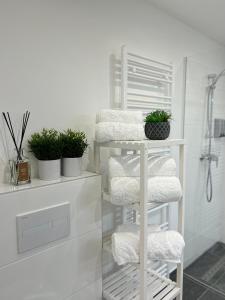 een wit handdoekenrek met handdoeken en planten in de badkamer bij Beatrix Home Vienna Luxury Stay in Wenen