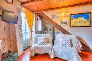 two white chairs in a room with a tv at Apartments In The Heart of Medieval Village - Happy Rentals in Apricale