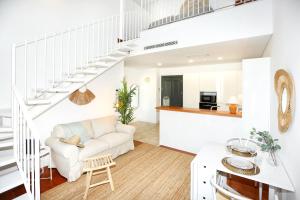 a white living room with a white couch and stairs at Watermelon Sugar Apartment in Faro