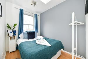 a bedroom with a bed with a blue blanket and a window at Impeccable 4-Bed House in Brixton London in London