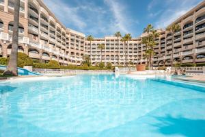 une grande piscine en face d'un grand bâtiment dans l'établissement Résidence Pierre & Vacances Cannes Verrerie, à Cannes