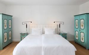 a bedroom with a white bed and two blue cabinets at Hotel Der Seehof in Goldegg