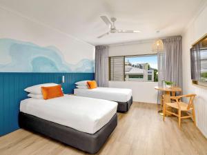 ein Hotelzimmer mit 2 Betten und einem Tisch in der Unterkunft Mercure Cairns in Cairns