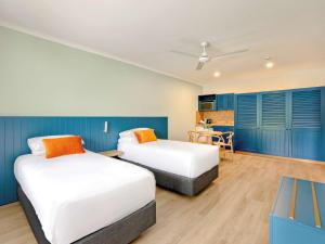 two beds in a room with blue cabinets at Mercure Cairns in Cairns