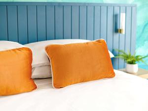 a bed with two orange pillows on it at Mercure Cairns in Cairns