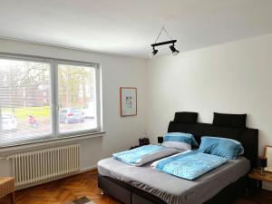 een slaapkamer met een bed met blauwe kussens en een raam bij Modern-Vintage Apartment in Osterholz-Scharmbeck