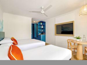 a hotel room with two beds and a table at Mercure Cairns in Cairns