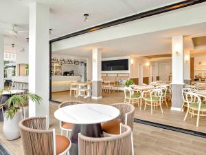 a restaurant with tables and chairs and a kitchen at Mercure Cairns in Cairns