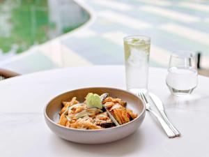 a bowl of pasta on a table with a glass of water at Mercure Cairns in Cairns