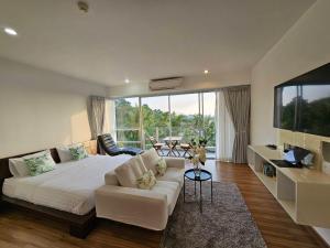 Sunset Residence Karon Beach في شاطئ كارون: غرفة نوم بسرير ابيض ونافذة كبيرة