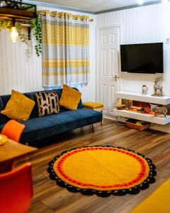 uma sala de estar com um sofá azul e um tapete amarelo em Wooden Cosy Retreat Hunters Quay em Dunoon