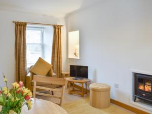 a living room with a fireplace and a chair at Rinnes Cottage in Aberlour