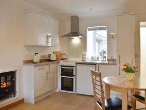 a kitchen with white cabinets and a table and a fireplace at Rinnes Cottage in Aberlour