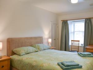 Un dormitorio con una cama con sábanas verdes y una ventana en Rinnes Cottage en Aberlour