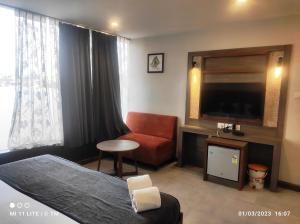 um quarto de hotel com uma cama, uma televisão e uma cadeira em HOTEL K79 em Jamshedpur