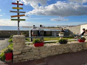 Un panneau directionnel avec des gens assis à une table près de l'océan dans l'établissement La Rose des Sables, à Tréffiagat