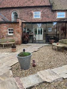 un patio con dos bancos y un pájaro en una olla en Newsham Grange Farm, en Thirsk