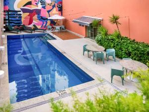 a swimming pool with tables and chairs next to a building at ibis Styles Belem Nazare in Belém