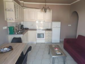 kuchnia z białymi szafkami, stołem i czerwoną kanapą w obiekcie Monemvasia Lazarus Beach Apartment w mieście Monemwasia