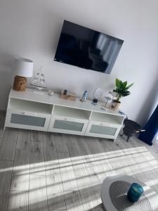 a living room with a white cabinet with a flat screen tv at Apartament 2B-4 Żarnowska in Żarnowska