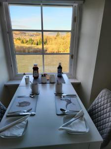 a table with plates and utensils and a window at Langhouse Castle Bed and Breakfast in Inverkip